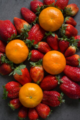 Strawberries and oranges on dark grey background. Fruits top view photo.  Fruit diet concept. 