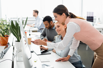Smiling businesswomen using graphics tablet and computer in office