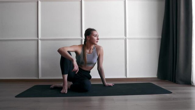 woman wearing sportswear sitting on yoga mat at home before workout bored