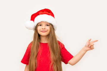 A happy little girl points her finger to the side on a white background.