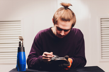 A shoemaker cuts the sole of a Shoe with a shoemaker's automatic cutter.