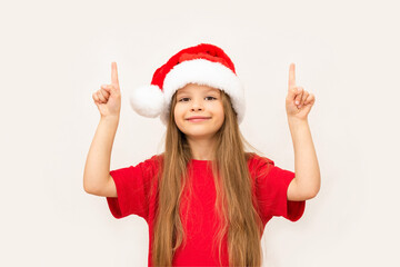 A little girl in a Christmas hat points up.