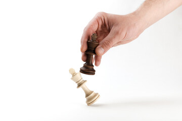 hand holds a chess king piece and defeats another king
