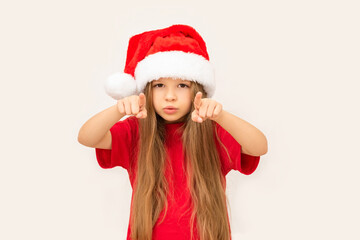 A little happy girl in a new year's hat points her fingers forward.