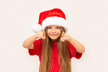 A little happy girl in a new year's hat points her fingers forward.