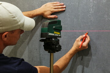a builder works with a laser  construction level.