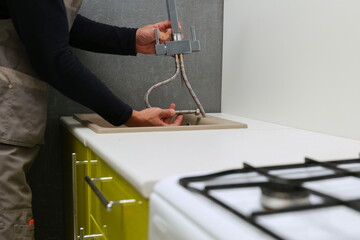 Fototapeta na wymiar plumber installs kitchen faucet close up