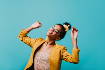 Fashionable black girl in yellow jacket happy dancing. Enthusiastic african female model chilling...