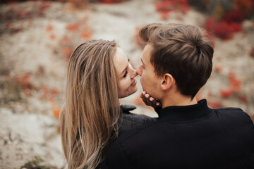 Close up of young beautiful couple of blonde smiling girl and handsome guy hugging outdoors at autumn season and smiling. 