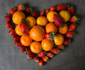 Strawberries and oranges on dark grey background. Fruits top view photo.  Fruit diet concept. 