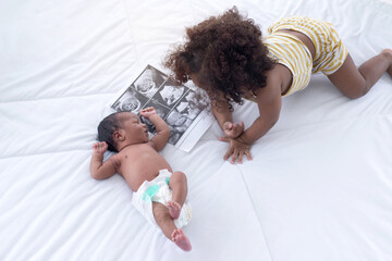 Dark skinned brother expressing love for his little baby sister at outdoor park, adorable sister...