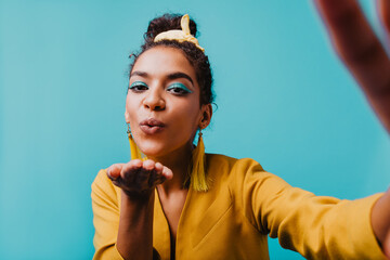 Elegant african woman in yellow jacket making selfie. Charming brunette girl sending air kiss.