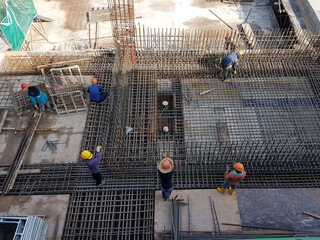 SHAH ALAM, MALAYSIA -MARCH 23, 2020: Construction workers fabricating steel reinforcement bar at the construction site. They tied it together using the tiny wires before cover it up timber formwork. 