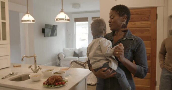 Mom dancing with baby in the kitchen during family holiday gathering 