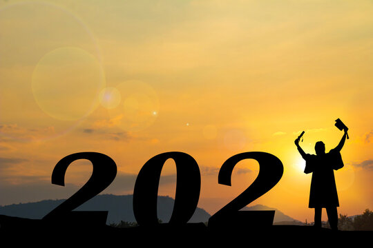 Happy new year Silhouette sunset background. He is wearing  graduate's dress and standing instead number 1 word. A man standing next to 2.new year,success,2021,Photo Silhouette and new year.