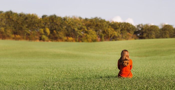 beautiful young woman sitting on green grass in autumn clothing, girl relax in solitude on nature