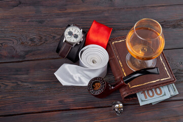 Top view mens items on wooden table. Glass of cognac and book on wooden table.