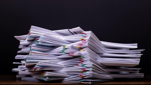 4K Stop motion of close-up stack overload document report paper with paperclip place increase on black background, business and education concept footage paperless used. 