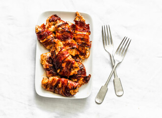 Baked bbq chicken breast wrapped in ham on a light background, top view. Delicious tapas, snack