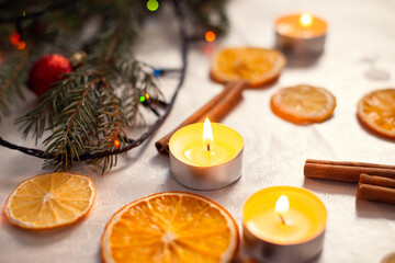 Still life picture of dried orange, candles, branches of fir-tree on a white table. Christmas decorations