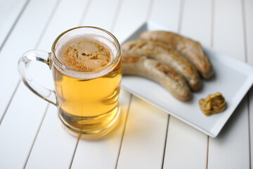 Light beer mug with fried sausages