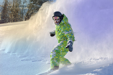 Snowboarder on snowboard rides through snow, explosion. Freeride in winter Ski Resort