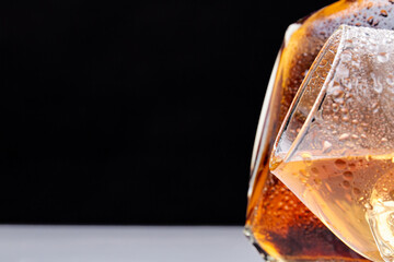 Close-up glass of whiskey with drops and copy space. Isolated on black background.