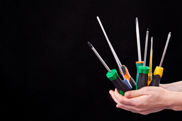 Hands holding set of screwdrivers. Isolated on black background.