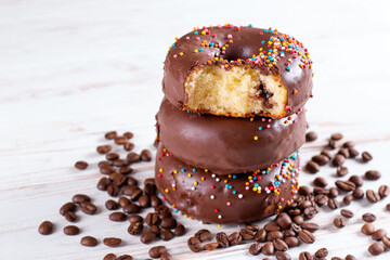 Delicious fresh chocolate donuts with coffee on white wooden background. Appetizing tasty glazed donuts ready to eat