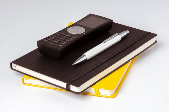Carnets de note jaune et noir avec un stylo et un téléphone posés