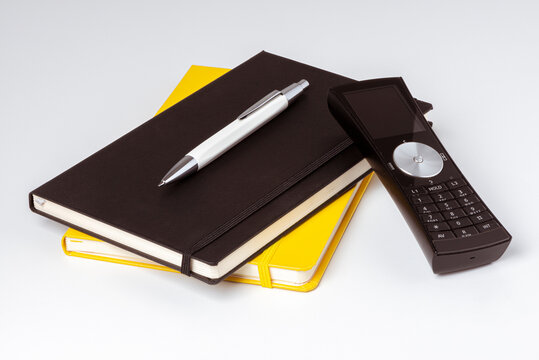Carnets de note jaune et noir avec un stylo et un téléphone posés