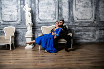 young couple in evening dresses sitting on a white couch in the dance hall