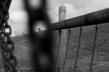 Park bench view through a chain black and white 