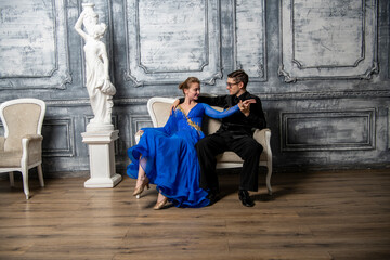 young couple in evening dresses sitting on a white couch in the dance hall
