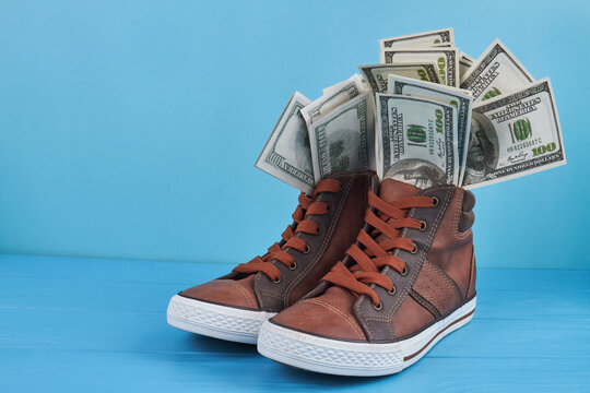 Sneakers shoes with dollar banknotes. Blue wooden table.