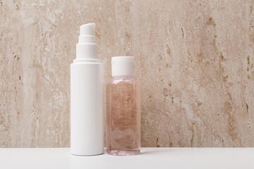 Face cream and skin lotion on white table against marble wall