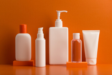 Set of five skin care products in white unbranded containers on orange background