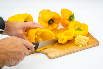 An men cutting yellow peper on a wooden cutting board