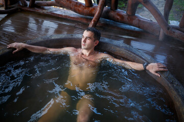 Young man in the pool with hot water on the terrace, spa body treatments. Outdoor Jacuzzi. Jacuzzi...