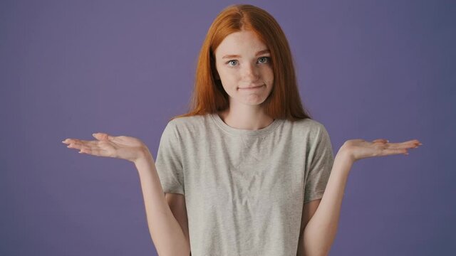 An attractive young woman is shrugging shoulders standing isolated over a violet background