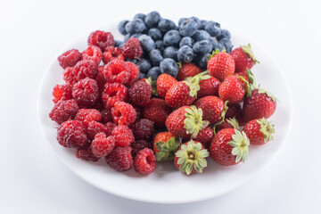 Fresh berries raspberries, strawberries and blueberries in plate isolated on white background, top view