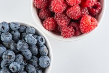 Fresh berries raspberries and blueberries in bowls isolated on white background, top view