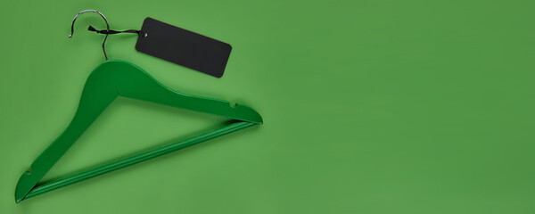 Wooden hanger with black paper label isolated on green paper background. Seamless pattern mockup...