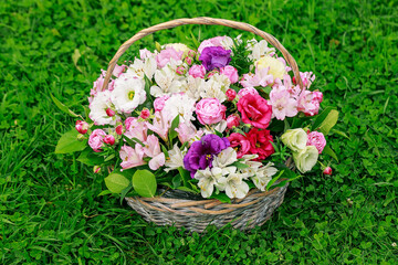 Large gift basket with flowers on a green lawn. Beautiful bouquet of bright flowers.