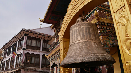 Obraz premium Huge metal clock mounted to a Buddhist temple near famous Boudhanath stupa (Boudha) in Kathmandu, Nepal. Text/symbols on clock: Buddhist mantras and prayers.