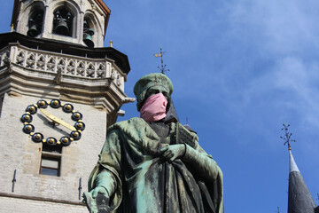 Fototapeta na wymiar The Aalst landmark statue of Dirk Martens wearing a mouth mask. A humorous reminder to locals to comply with COVID 19 regulations and to wear a face covering.