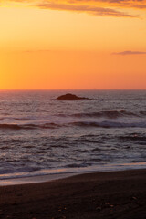 Sunset over the ocean with a rock