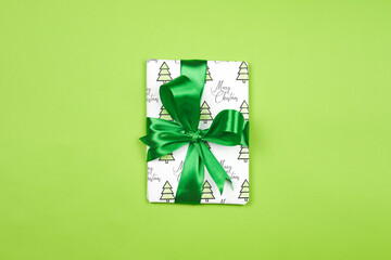 X-mas gift wrapped in paper with Christmas prints and tied with black ribbon. Christmas present box on white background