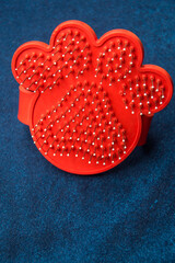 Red dog paw print brush on a blue table to  comb our pets 