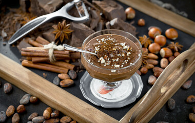 Dark chocolate in a composition with cocoa beans and nuts, on an old background.
